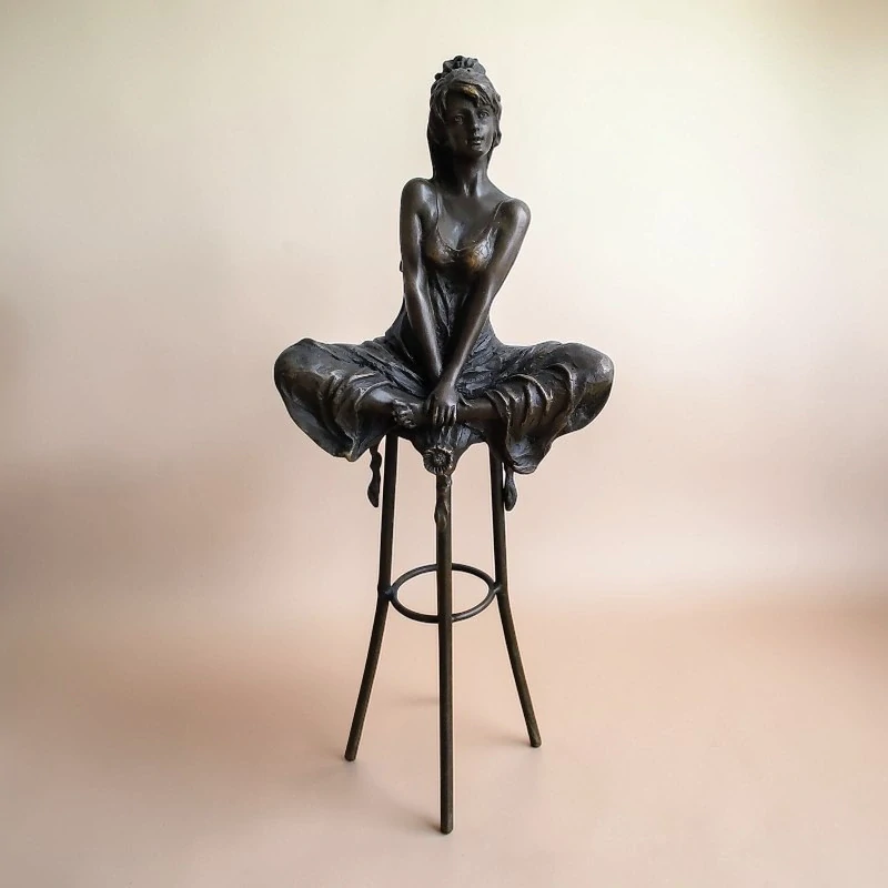 Elegantní bronzová socha sedící ženy na barové stoličce